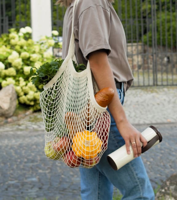 A man is carrying a bag full of groceries.