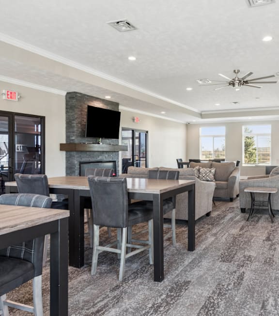 A modern dining room with a stone fireplace and a flat screen TV above it.