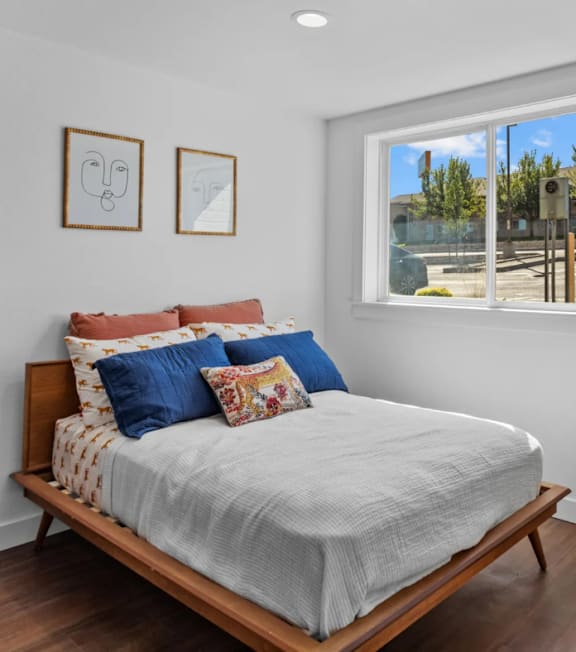A bed with a white sheet and a wooden headboard with a window in the background.