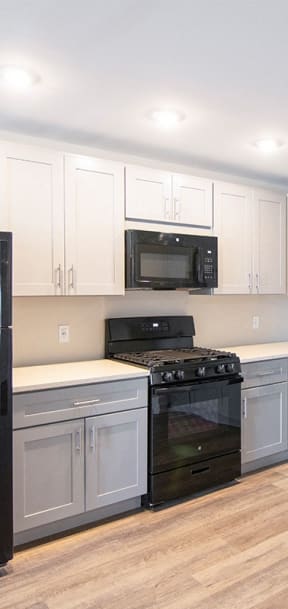 a kitchen with white cabinets and a black stove and refrigerator