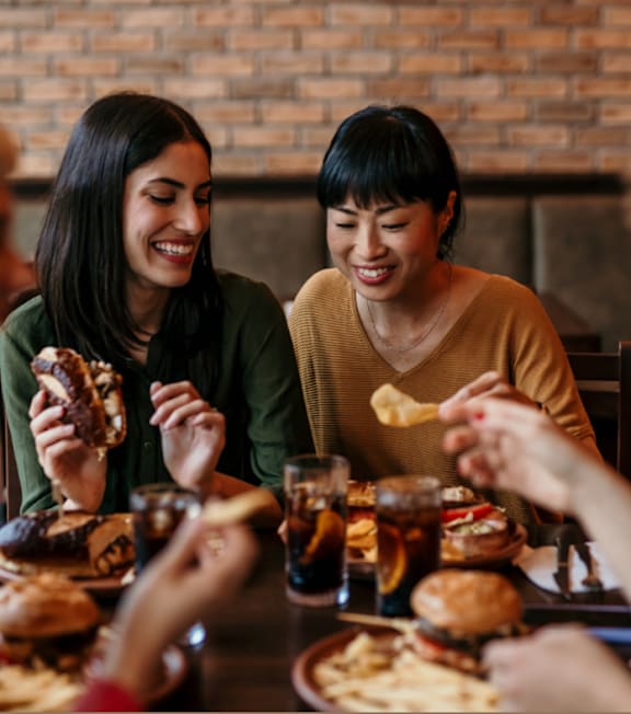 Two women enjoying burgers and fries at a table.