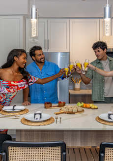 Four people are standing around a table with food and drinks.