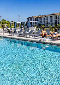 A swimming pool with people relaxing by the poolside.
