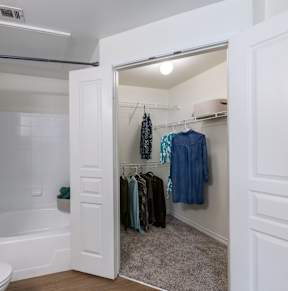 A white bathroom with a toilet, a bathtub, and a walk-in closet.