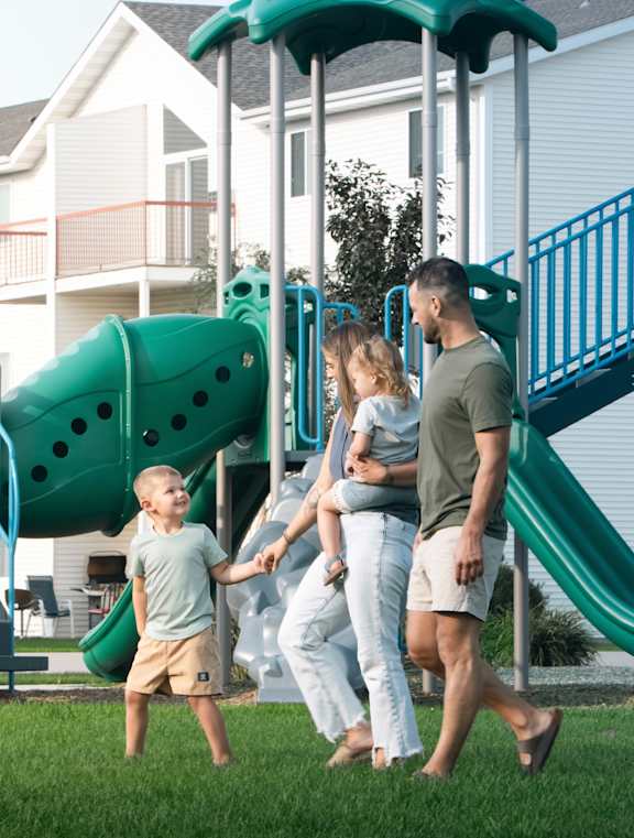 A young child is swinging on a swing with an adult holding the other end.