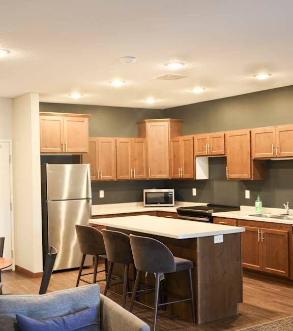 A kitchen with a white island and wooden cabinets.