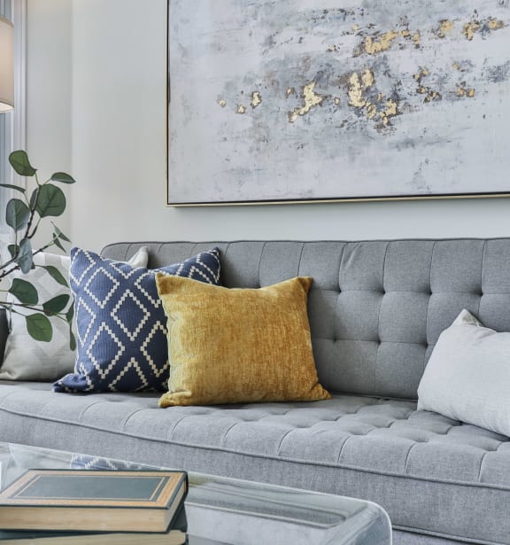 a living room with a gray couch and blue and white pillows