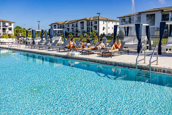 Group of people chilling on sun loungers by the pool at Portofino Vineyards, Fort Myers, FL