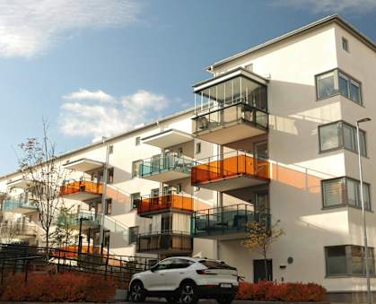 A white and orange building with a car parked in front.