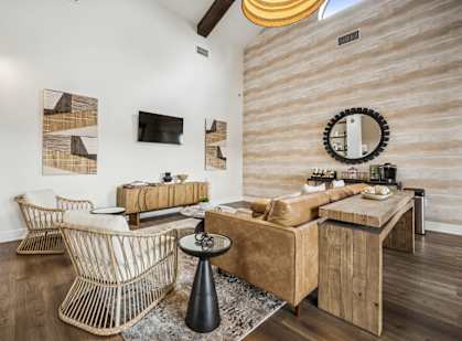 A living room with a brown couch and a woven chair.