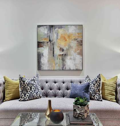 a living room with a gray couch and yellow and blue pillows