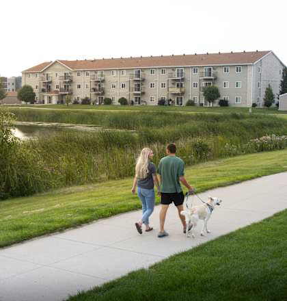 A man and woman walking a dog on a path.
