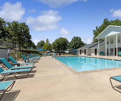 A pool with sun loungers and a building in the background.