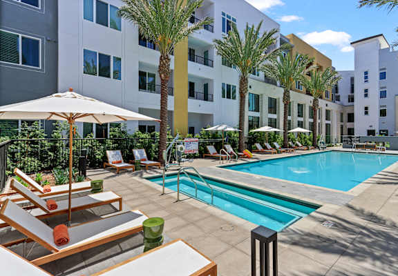 a swimming pool with lounge chairs and a building in the background