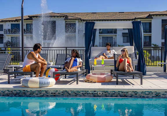 Four people are sitting by the pool with a fountain in the background at Portofino Vineyards, Fort Myers, FL, 33967