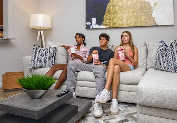 Three people are sitting on a couch with popcorn and watching television at Portofino Cove, Fort Myers