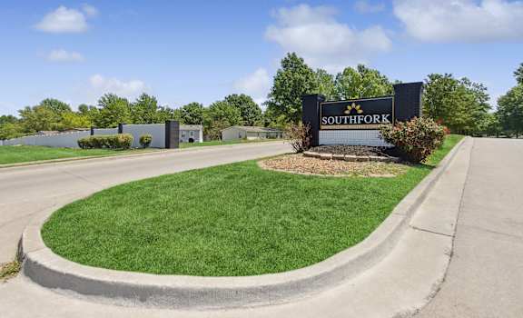 A sign that says Southfork in front of a grassy area.
