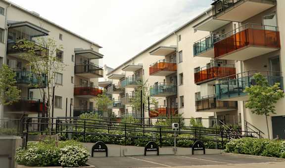 Apartment complex with a black fence and green plants.