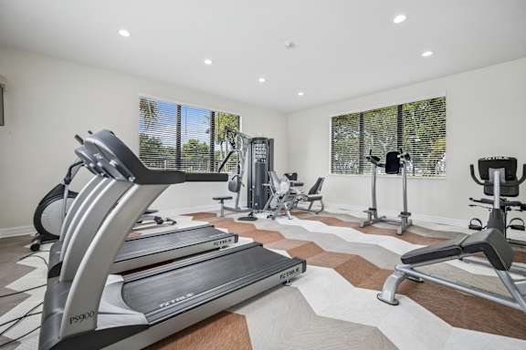 A home gym with treadmills, elliptical machines, and other exercise equipment.