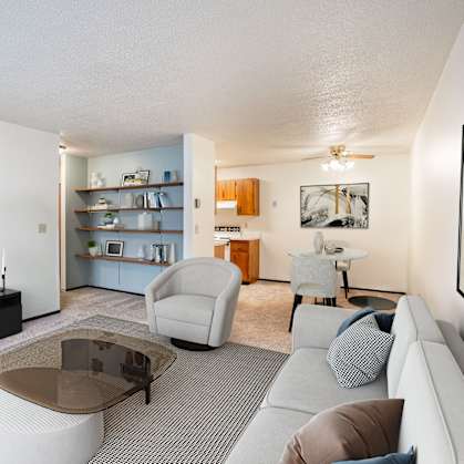 A living room with a grey sofa, a glass coffee table, and a television. Fargo, ND Countryside Apartments