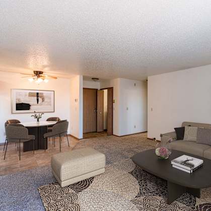 a living room with a couch and a coffee table and a dining room. Fargo, ND Auburn II Apartments