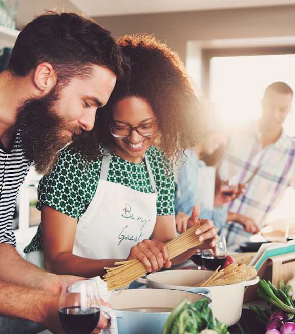 A man and woman are cooking together in a kitchen.