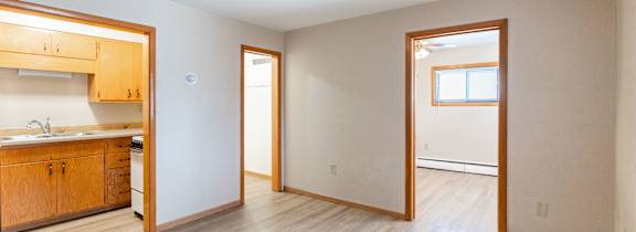 A kitchen with wooden cabinets and a wood flooring. Fargo, ND Birchwood Apartments