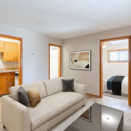 A living room with a couch, a coffee table, and a television. Fargo, ND Birchwood Apartments