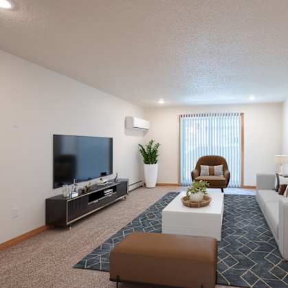 A living room with a white couch, a brown ottoman, a television, and a plant. Grand Forks, ND Cherry Creek Apartments