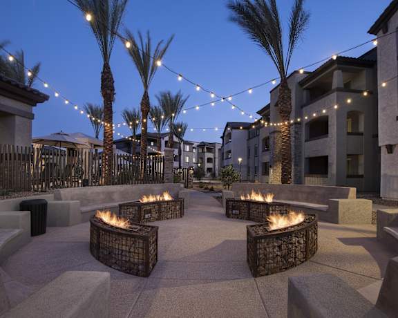 a patio with fire pits at night at theiances apartments