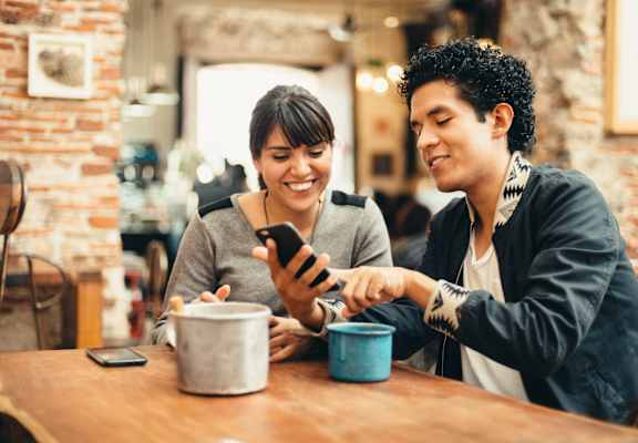 a man and woman sitting at a table looking at a cell phone at Midtown Sam Houston Apartments, Huntsville, TX, 77340