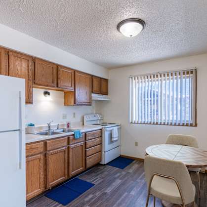 a kitchen with a dining table and a refrigerator. Grand Forks, ND Chandler 1898 Apartments