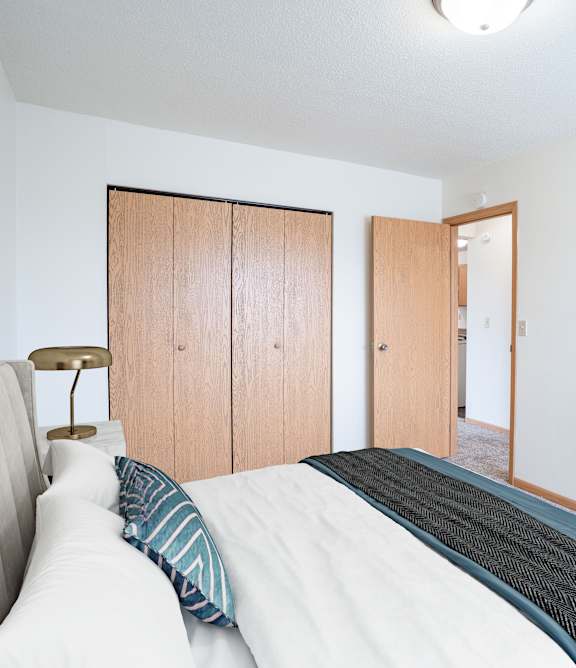 Bismarck, ND Stonefield Townhomes | Living Room A bedroom with a bed, a lamp, and a painting on the wall. West Fargo, ND Saddlebrook Apartments