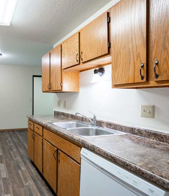 Bismarck, ND Stonefield Townhomes | Living Room A kitchen with a white fridge and wooden cabinets. Grand Forks, ND Columbia West Apartments