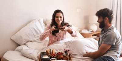 couple eating breakfast in bed in a hotel room
