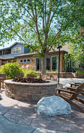 A backyard with a fire pit and chairs.