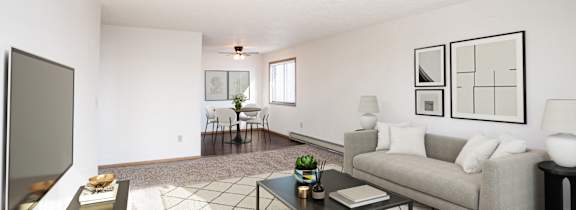 A living room with a grey couch, a black coffee table, and a television on the left side. Fargo, ND Fieldstone Apartments
