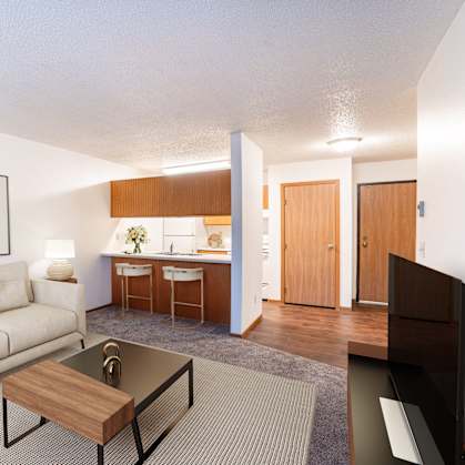 A living room with a couch, coffee table, and a painting on the wall. Fargo, ND Candlelight Apartments