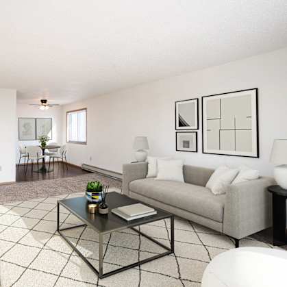 A living room with a grey couch, a black coffee table, and a television on the left side. Fargo, ND Fieldstone Apartments