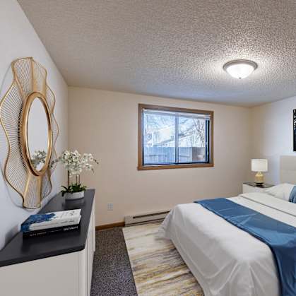 a bedroom with a white bed and a blue blanket. Fargo, ND Berkshire Apartments