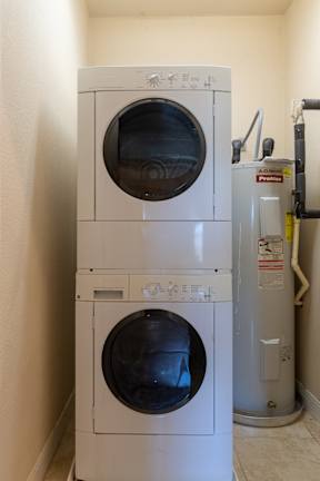 A white dryer and washer are stacked on top of each other. at Logan Ridge Apartments, Apartments, San Marcos, TX