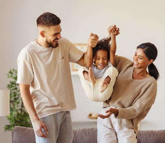 a young family is playing with their daughter in the living room