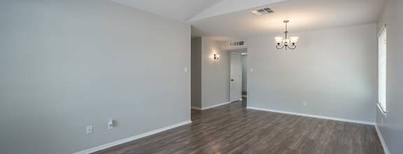 A room with wooden flooring and a chandelier.