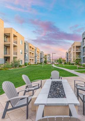A patio with a table and chairs is surrounded by apartment buildings.
