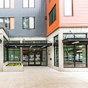 A modern multi-story building with balconies and glass doors.
