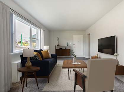 A living room with a blue couch, a wooden coffee table, and a flat screen TV mounted on the wall.