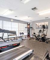 A spacious gym with a treadmill, exercise bike, and other equipment.