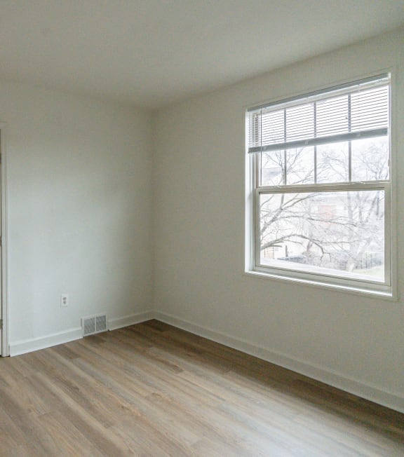 a bedroom with white walls and a window and wooden floors