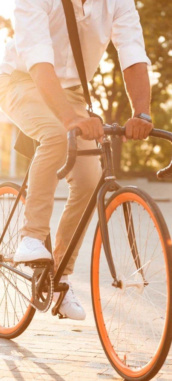 A man in a white shirt and beige pants is riding a bicycle.