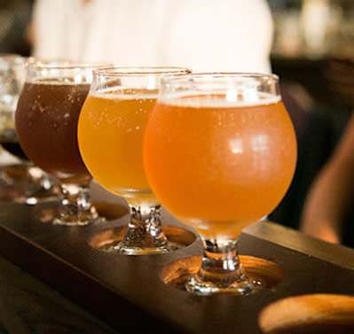 A row of glasses filled with different colored beer.